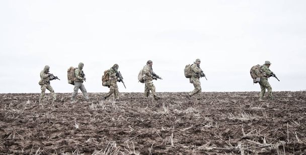 Группа солдат армии марширует по грязному полю
 - Фото, изображение