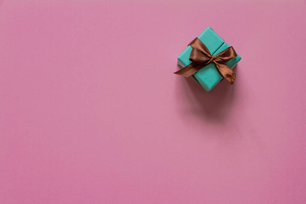 Turquoise gift or present box with brown ribbon on pink table top view. Flat lay. Birthday, wedding or christmas concept. - Foto, Imagem