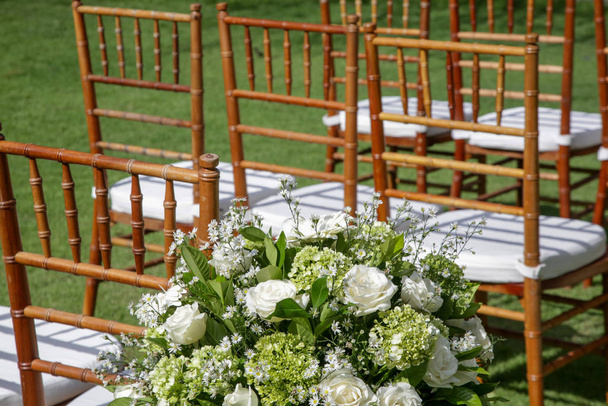 Kaunis romanttinen ulkona häät setup trooppisessa puutarhassa, puiset tuolit koristeltu valkoisia kukkia
 - Valokuva, kuva