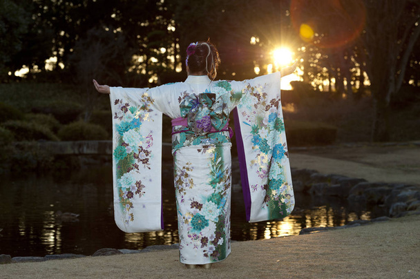 Japonský teenager v tradičním kimonu se zády a pažemi roztaženými s krásnou světlicí a slunečním svitem oslavující Den příchodu věku v japonském Fuji City. Vodorovný záběr. - Fotografie, Obrázek