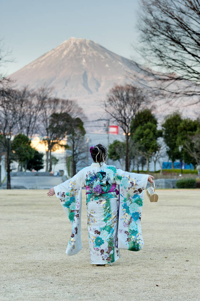 Adolescente giapponese che indossa il tradizionale kimono con le braccia tese contemplando la bellezza del Mt. Fuji celebra il Giorno dell'Età a Fuji City, Giappone. Colpo verticale
. - Foto, immagini