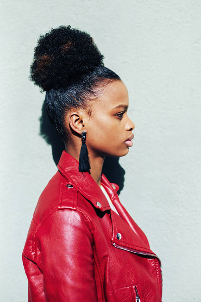 portrait of cheerful black teenage girl with healthy-looking skin and voluminous african hair, dressed in red Leather Jacke - Photo, Image