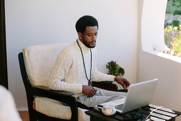 Portrait of black man using laptop at home. Freelance worker, freedom and enjoy summer day - Photo, Image