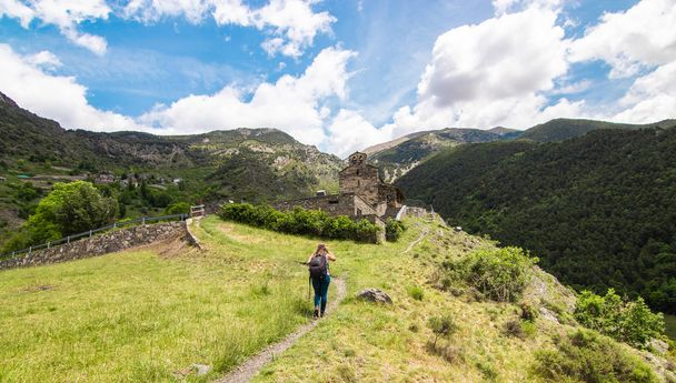 A young tourist woman during the hike in the Pyrenees mountains. On her way to the ancient church of Sant Serni de Nagol, located near Andorra La Vella, Andorra - Фото, изображение