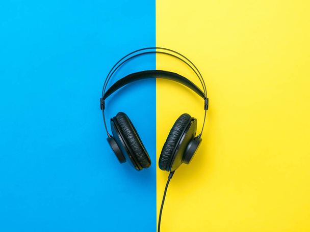 Μαύρα ακουστικά με σύρμα σε κίτρινο και μπλε φόντο. - Φωτογραφία, εικόνα