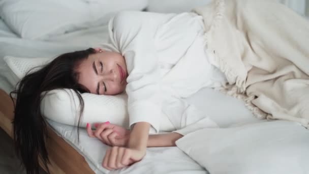 Portrait of pretty woman sleeps and wakes up in morning stretched in bed, smiles - Video