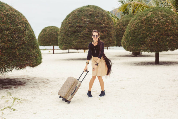 Beautiful style girl walking with suitcase on tropical beach - Foto, afbeelding