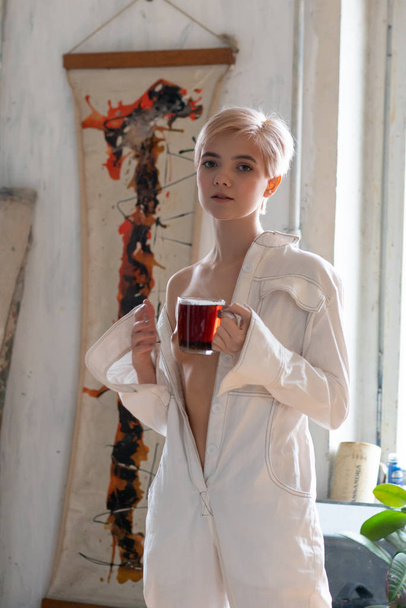 young beautiful drinks tea in white clothes - Photo, image