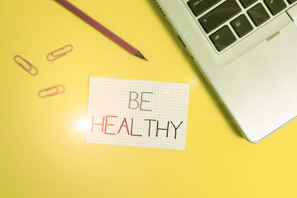 Word writing text Be Healthy. Business concept for to be vigorous and totally free from bodily or mental diseases Trendy metallic laptop clips pencil squared paper sheet colored background. - Fotoğraf, Görsel