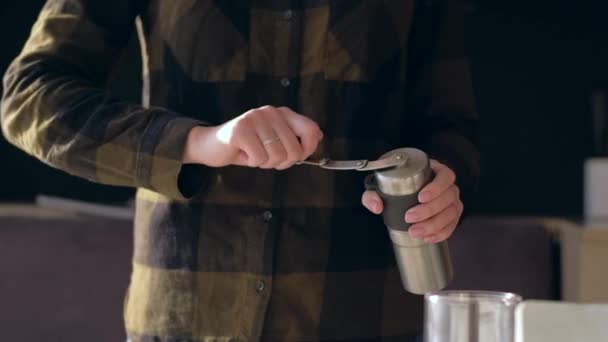 Handen vasthouden koffiemolen en wikkelen zijn handvat tijdens het malen van koffiebonen. - Video