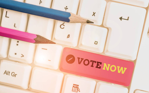 Handwriting text writing Vote Now. Concept meaning formal indication of choice between two or more courses of action White pc keyboard with empty note paper above white background key copy space. - Photo, Image