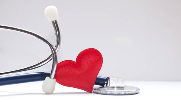 Gezondheidszorg concept: een rode stof hart in een stethoscoop op  - Foto, afbeelding