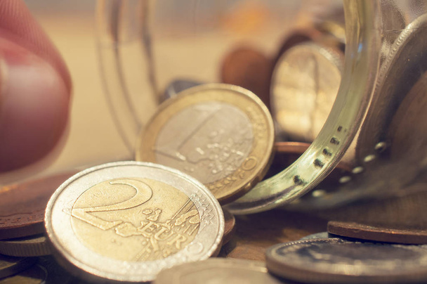 Ένα χέρι που παίρνει κέρμα από ένα ανατρεπόμενο βάζο νομισμάτων - Φωτογραφία, εικόνα