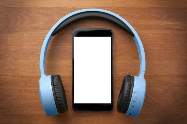 Par de auriculares azules alrededor de un teléfono inteligente de pantalla en blanco en oran
 - Foto, imagen