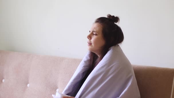 Άρρωστη νεαρή γυναίκα κάθεται στο σπίτι με μια καταραμμένη μύτη και φτερνίζεται - Πλάνα, βίντεο