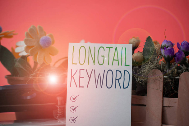 Writing note showing Longtail Keyword. Business photo showcasing search phrases that are highly relevant to specific niche Flowers and writing equipments plus plain sheet above textured backdrop. - Fotoğraf, Görsel