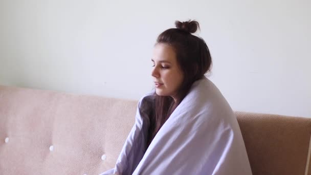 Beteg fiatal nő ül otthon egy folyós orral, és tüsszent - Felvétel, videó