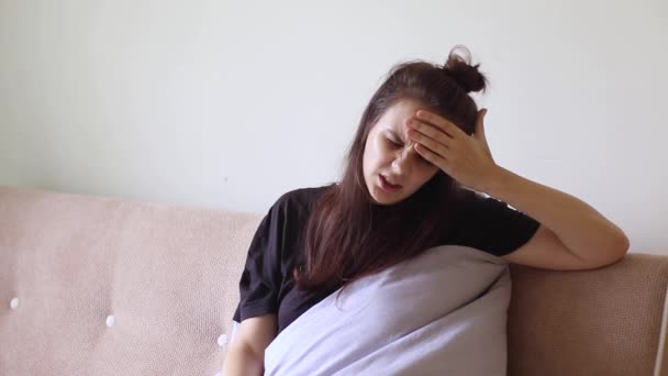 Nemocná mladá žena sedí doma s těžkou bolestí hlavy - Záběry, video
