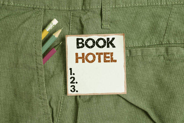 A Book Hotel felirata. Üzleti fotó bemutatja az elrendezést, hogy egy szállodai szoba vagy szállás Író berendezések és kék jegyzet papír zsebében nadrág. - Fotó, kép
