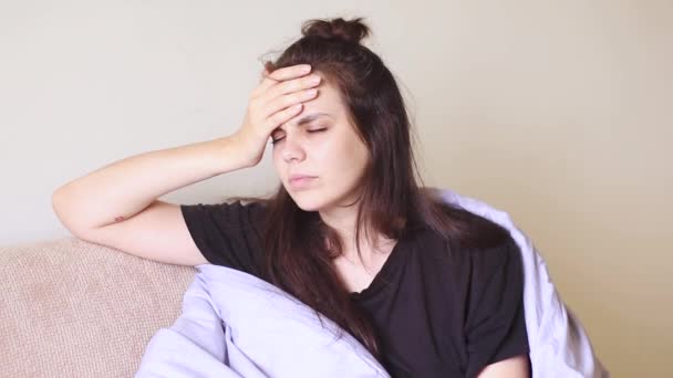 Nemocná mladá žena sedí doma s těžkou bolestí hlavy - Záběry, video