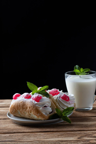Kefir is decorated with a leaf of mint, a fermented drink. Air cake on a saucer. wood background - Foto, imagen