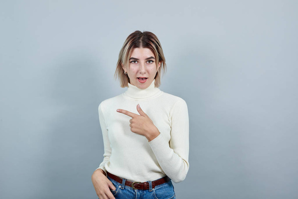 Attractive woman in casual shirt showing on workspace isolated on gray wall - Photo, Image