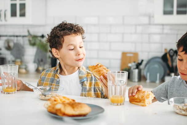 Dva sourozenci mezi chlapci skuteční bratři mají snídani na světlé kuchyni doma - Fotografie, Obrázek