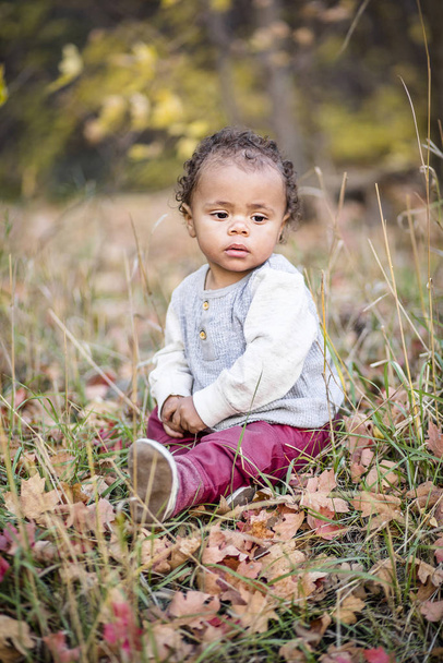 Kültéri portré egy gyönyörű nyugodt kevert fajú kisfiúról. Imádnivaló gyermek, nagyon aranyos arckifejezéssel. - Fotó, kép