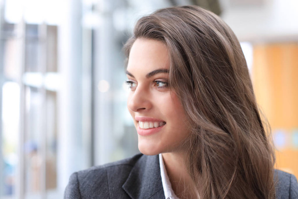 Attractive business woman smiling while standing in the office. - Фото, изображение