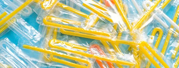 Pile of yellow drinking straws on a blue background - Фото, изображение