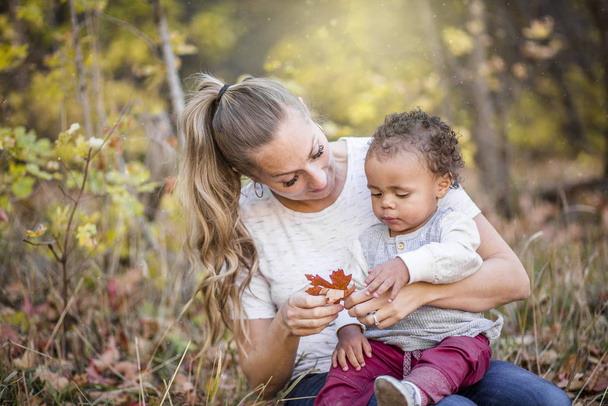 Beautiful candid portrait of a mother playing with her cute bi-racial son. Mother and child Spending time together in the outdoors - Photo, Image