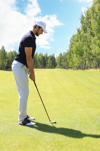 Full length of golf player playing golf on sunny day. Professional male golfer taking shot on golf course. - Φωτογραφία, εικόνα