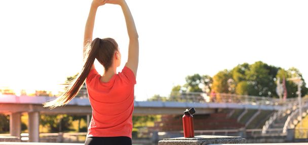 Jovem mulher fitness atraente vestindo roupas esportivas exercitando ao ar livre, exercícios de alongamento. - Foto, Imagem