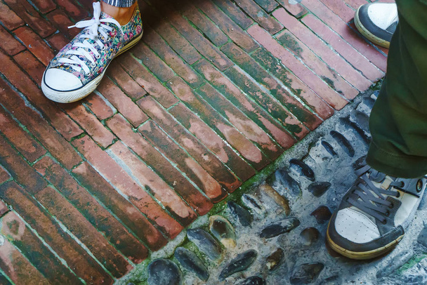 Ноги чоловіка і жінки, які носять спортивне взуття і стоять на міській вулиці в Італії. - Фото, зображення