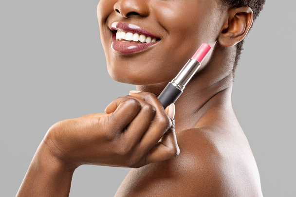 Afro žena drží růžové pomade blízko k obličeji a usmívá se - Fotografie, Obrázek
