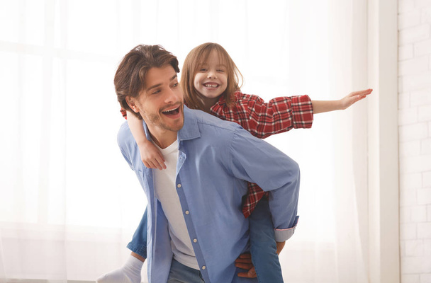 Funny daddy is holding his daughter on his back - Photo, Image
