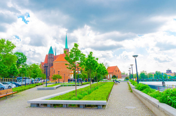Sts. Peter and Paul church, Collegiate Church of Holy Cross and St. Bartholomew, alley with grass lawn, green trees and Tumski bridge over Oder river in old historical city centre of Wroclaw, Poland - 写真・画像