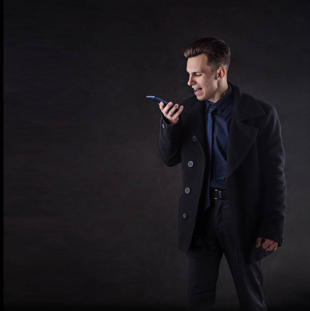 A handsome man in a coat screams while talking on the phone. - Foto, Imagem