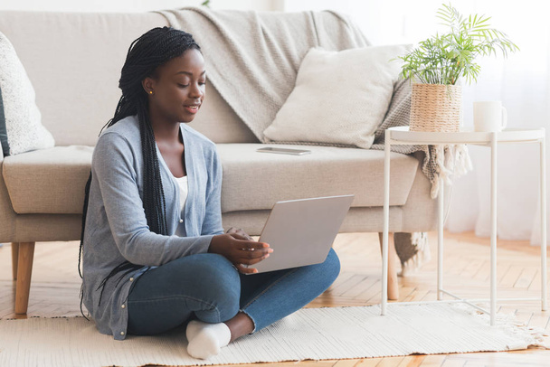 Afro κορίτσι κάθεται στο πάτωμα με φορητό υπολογιστή, εργασίας από το σπίτι - Φωτογραφία, εικόνα