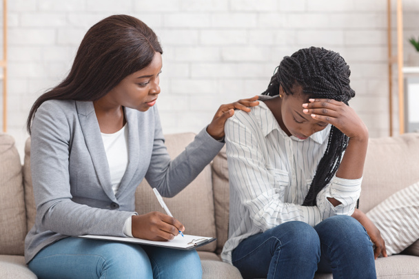 Female psychologist consoling depressed woman at personal consultation in office - Photo, Image