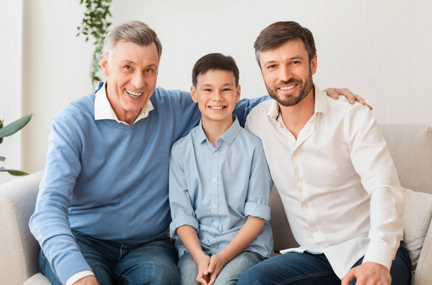 Мальчик с отцом и дедушкой сидит дома на диване
 - Фото, изображение