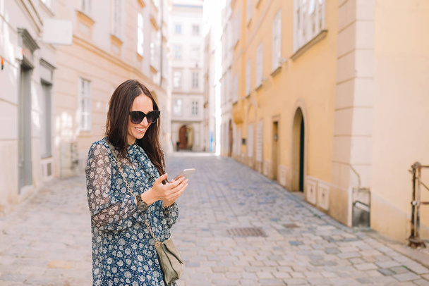 Woman talk by her smartphone in city. Young attractive tourist outdoors in italian city - 写真・画像
