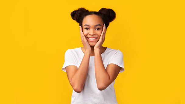 Sorridente adolescente nero che tiene le guance su sfondo giallo
 - Foto, immagini