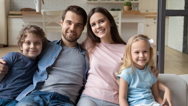 Beautiful full family sitting on couch smiling looking at camera - Photo, Image