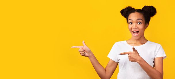 attraktiver schwarzer Teenager zeigt mit dem Finger auf freien Raum - Foto, Bild