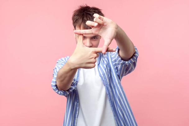 Frame of fingers. Portrait of young man with brunette hair looki - Foto, Imagem