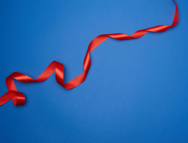 cinta delgada de seda roja retorcida sobre un fondo azul, classi de moda
 - Foto, imagen