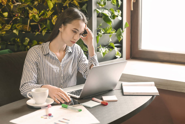 Стрессовая деловая женщина сидит, анализируя данные на ноутбуке в кафе
 - Фото, изображение