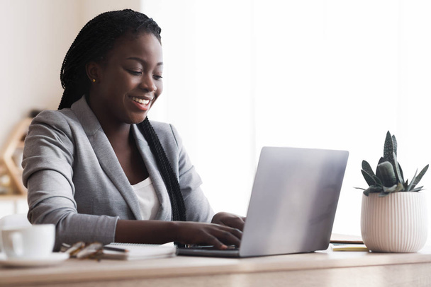 Negrita Millennial Businesswoman usando el ordenador portátil en la oficina moderna
 - Foto, imagen