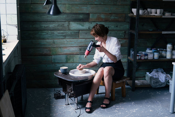 Portrait of Female potter wearing white shirt, business suit working with clay in workshop - Photo, image
